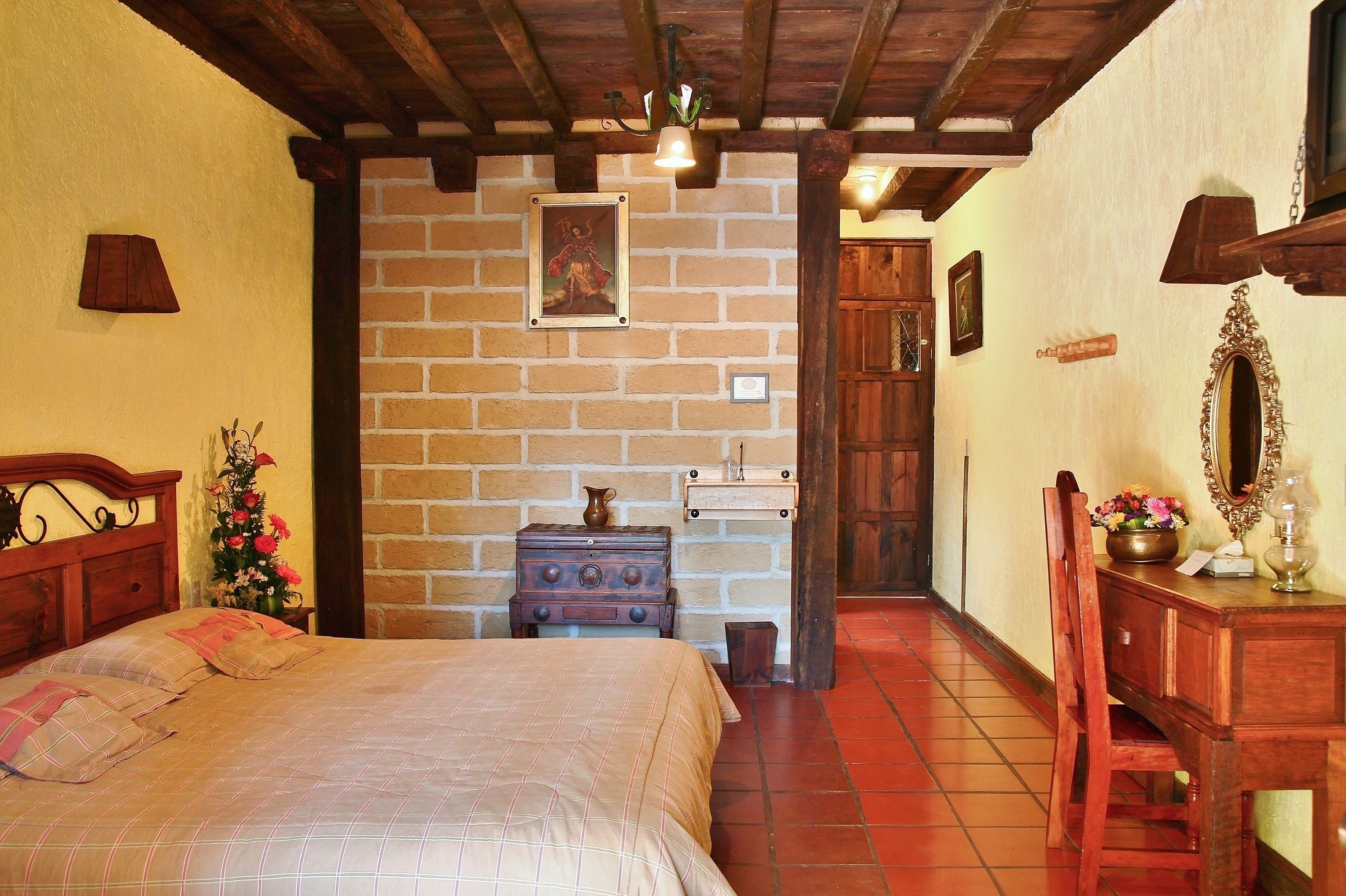 Una habitación acogedora con cama, muebles de madera, pared de ladrillo y techo de madera.