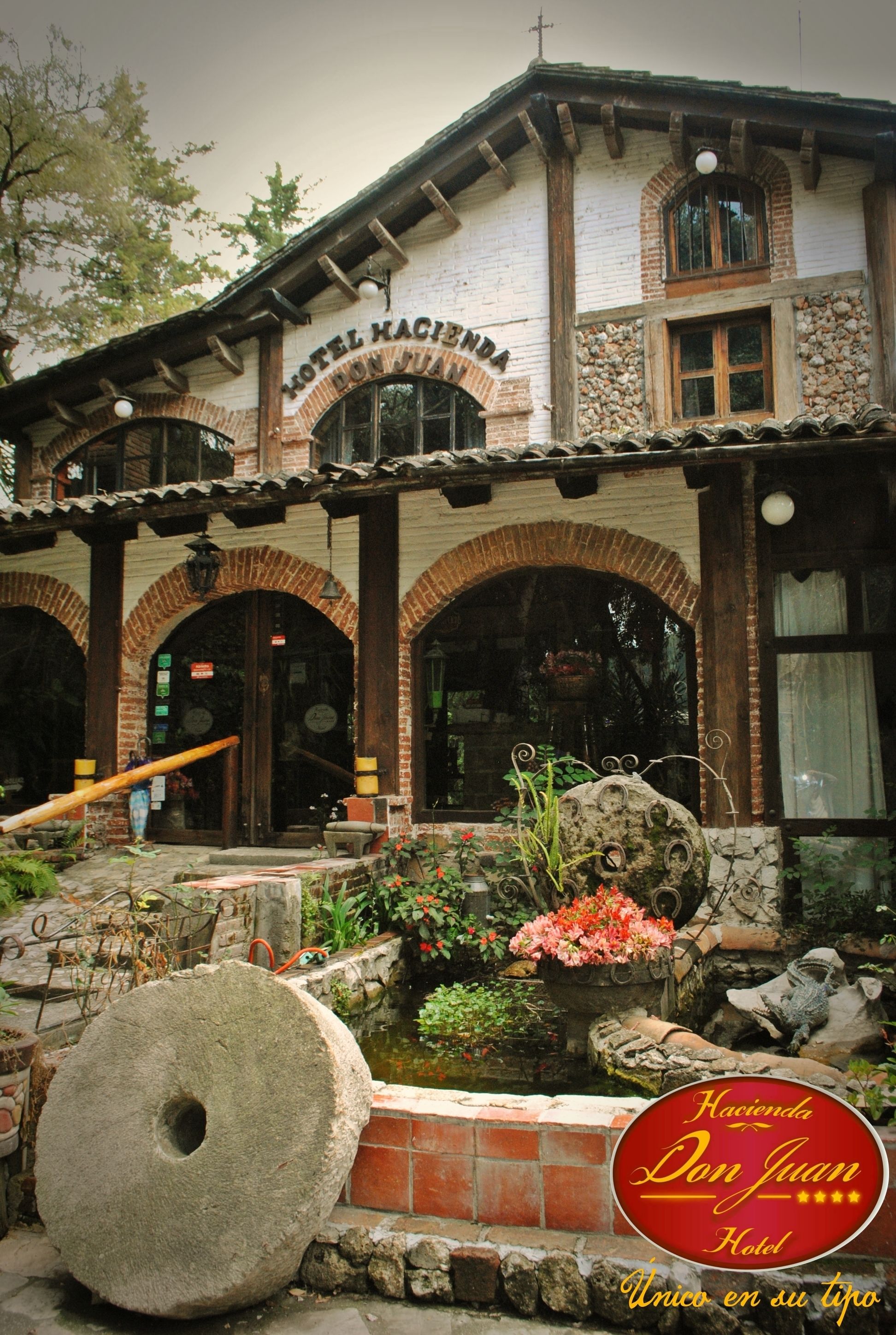 Un bâtiment historique doté d’une façade en pierre, de portes en arc de cercle et d’une enseigne indiquant « HÔTEL HACIENDA DON JUAN ».