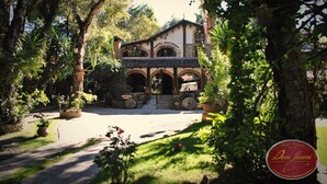 A traditional building with a tiled roof, arched doorways, and a stone facade. - Hotel Hacienda Don Juan  (San Cristóbal de las Casas)
