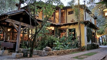 A rustic two-story building with a wooden balcony and a stone pathway leading to the entrance.