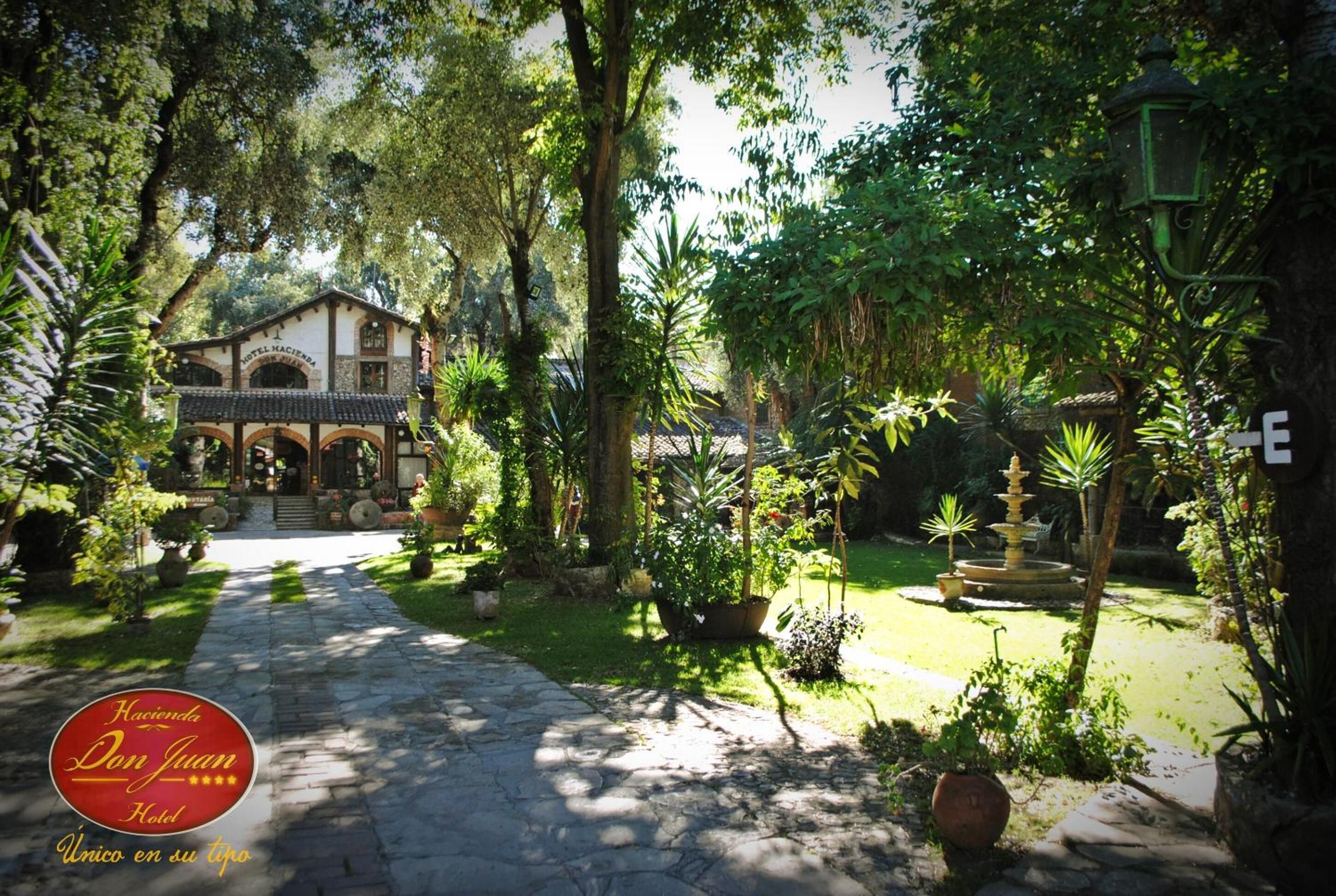 Een tuinpad dat leidt naar een gebouw met de tekst 'Hotel Hacienda'.