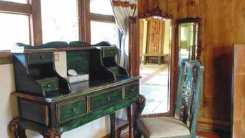 Una stanza con una scrivania in legno, una sedia, uno specchio e una finestra con tende.