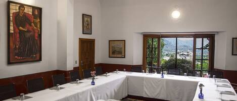 A conference room with long tables, chairs, a projector, and framed artwork on the walls.