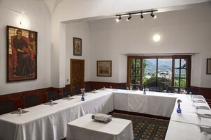 A conference room with long tables, chairs, a projector, and framed artwork on the walls.