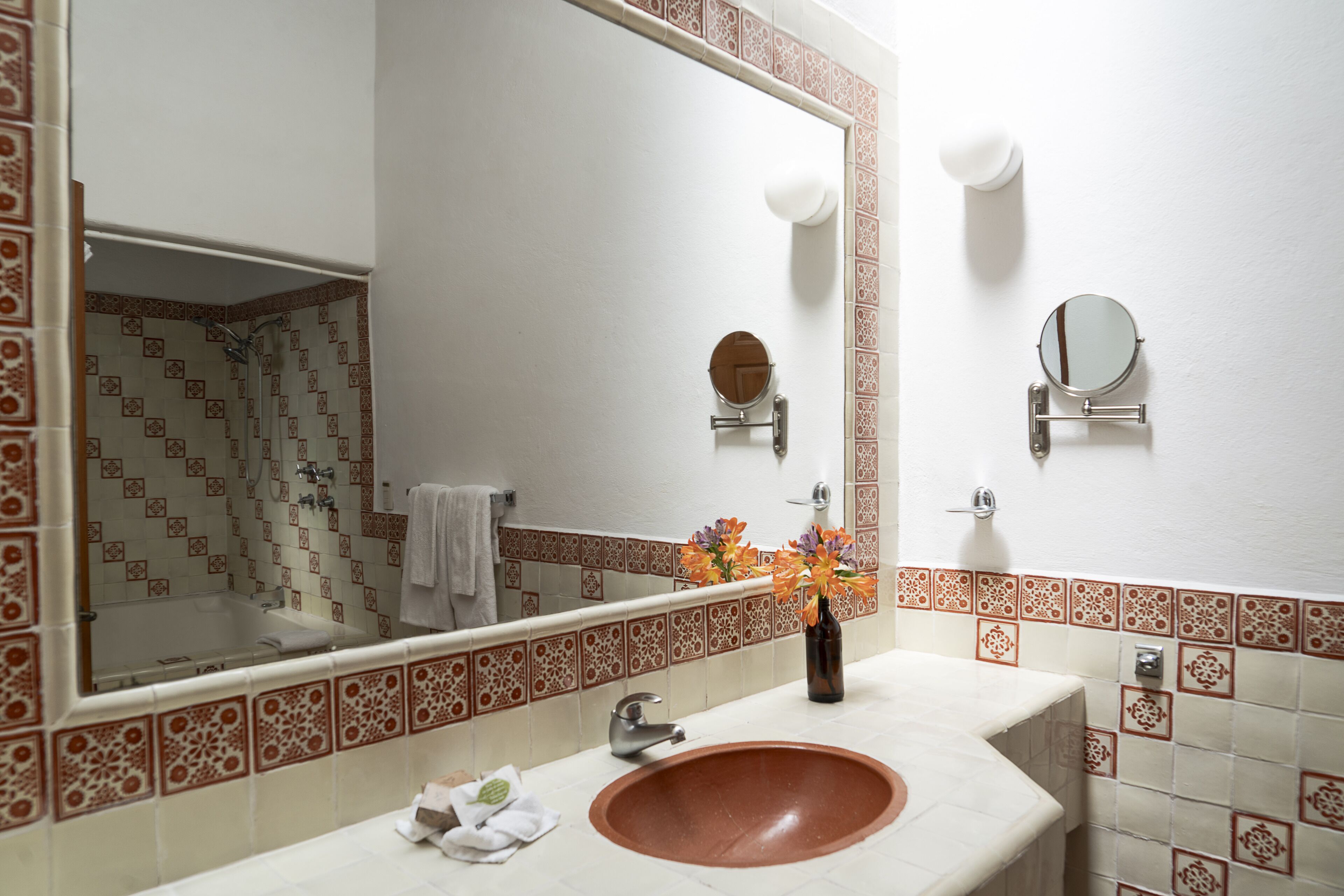 A bathroom with a large mirror, a sink, and a shower.