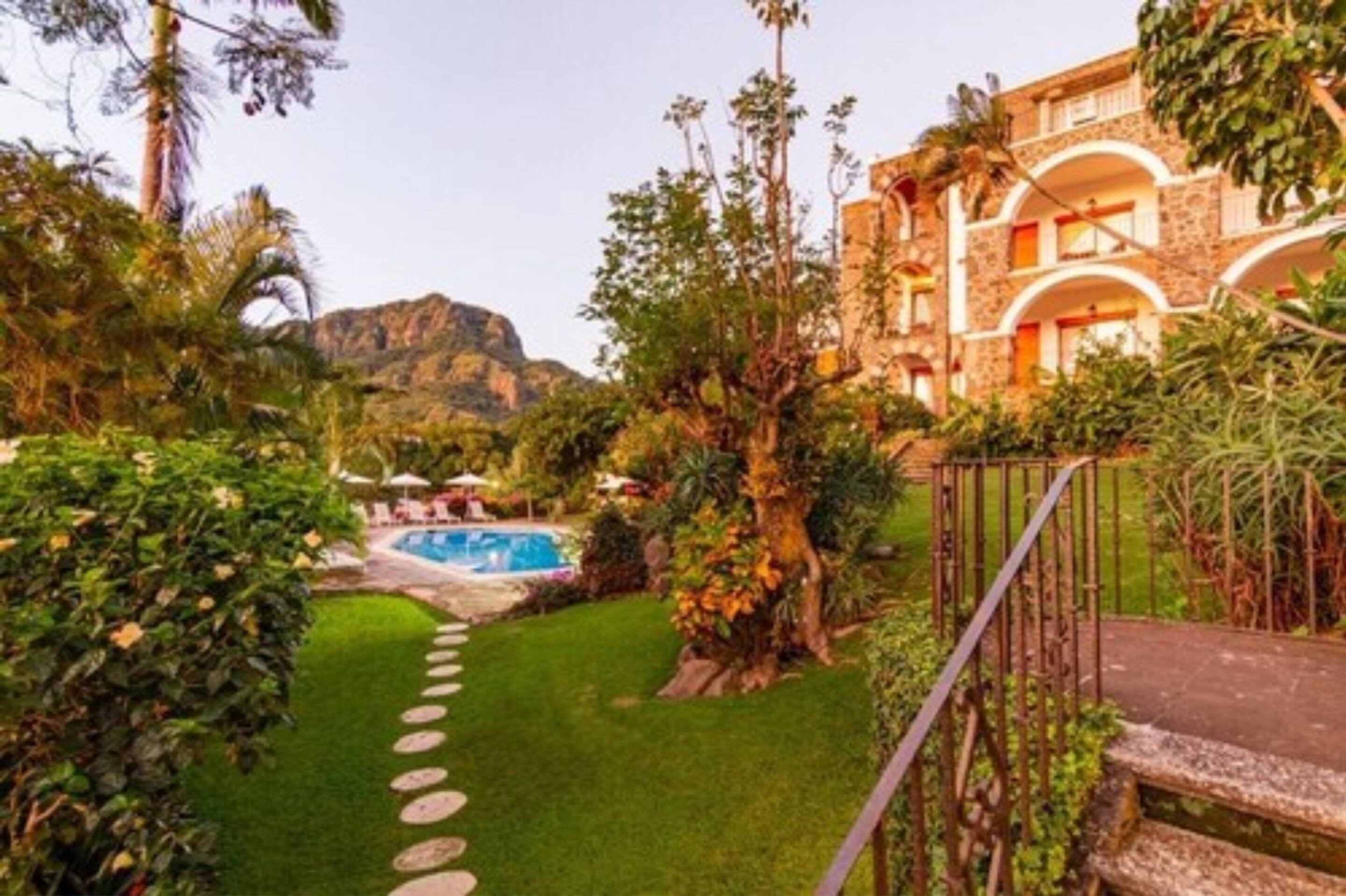 Ein Hotel mit Pool, üppigem Garten und Bergblick.