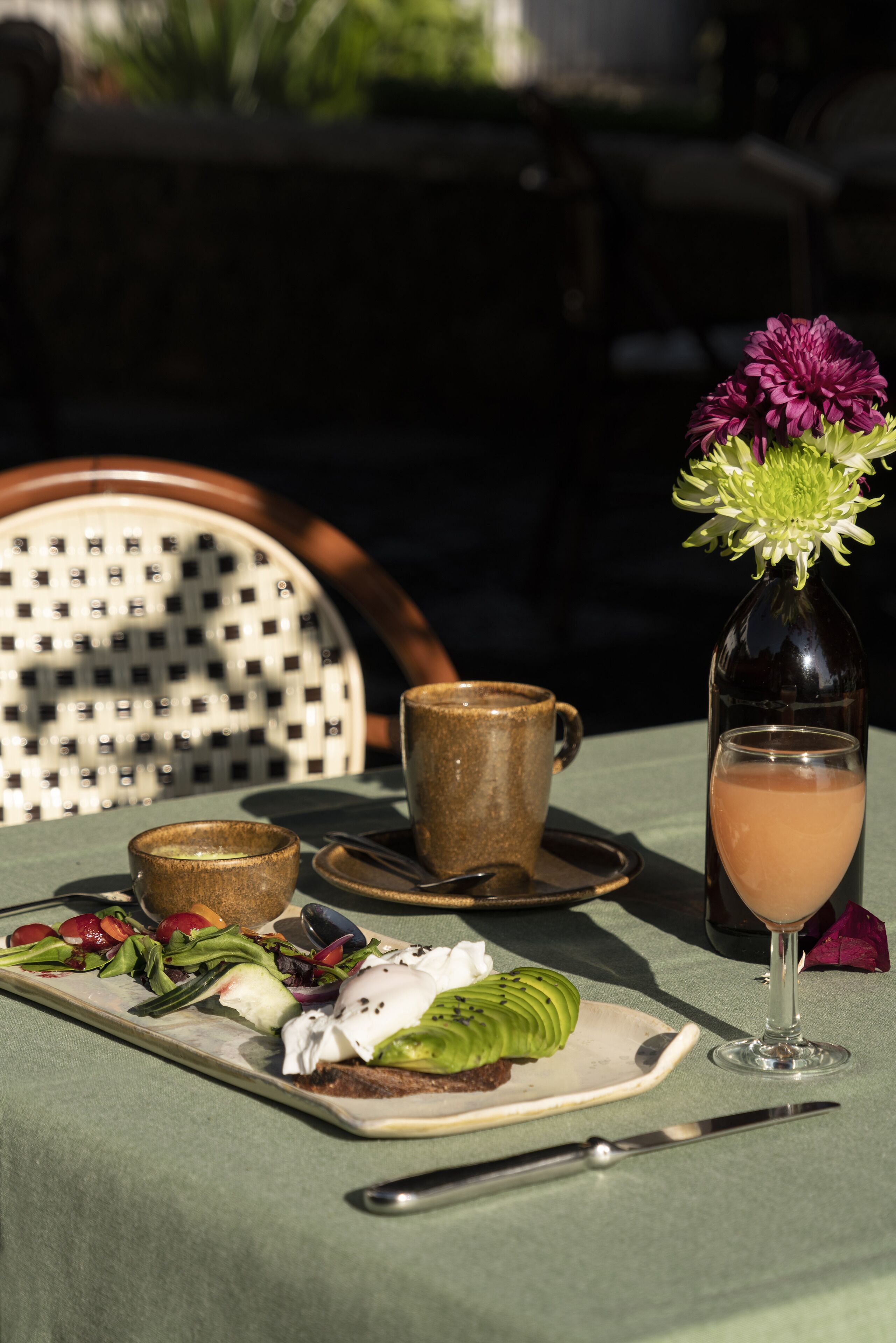 A table set with a meal, a drink, and a decorative flower.