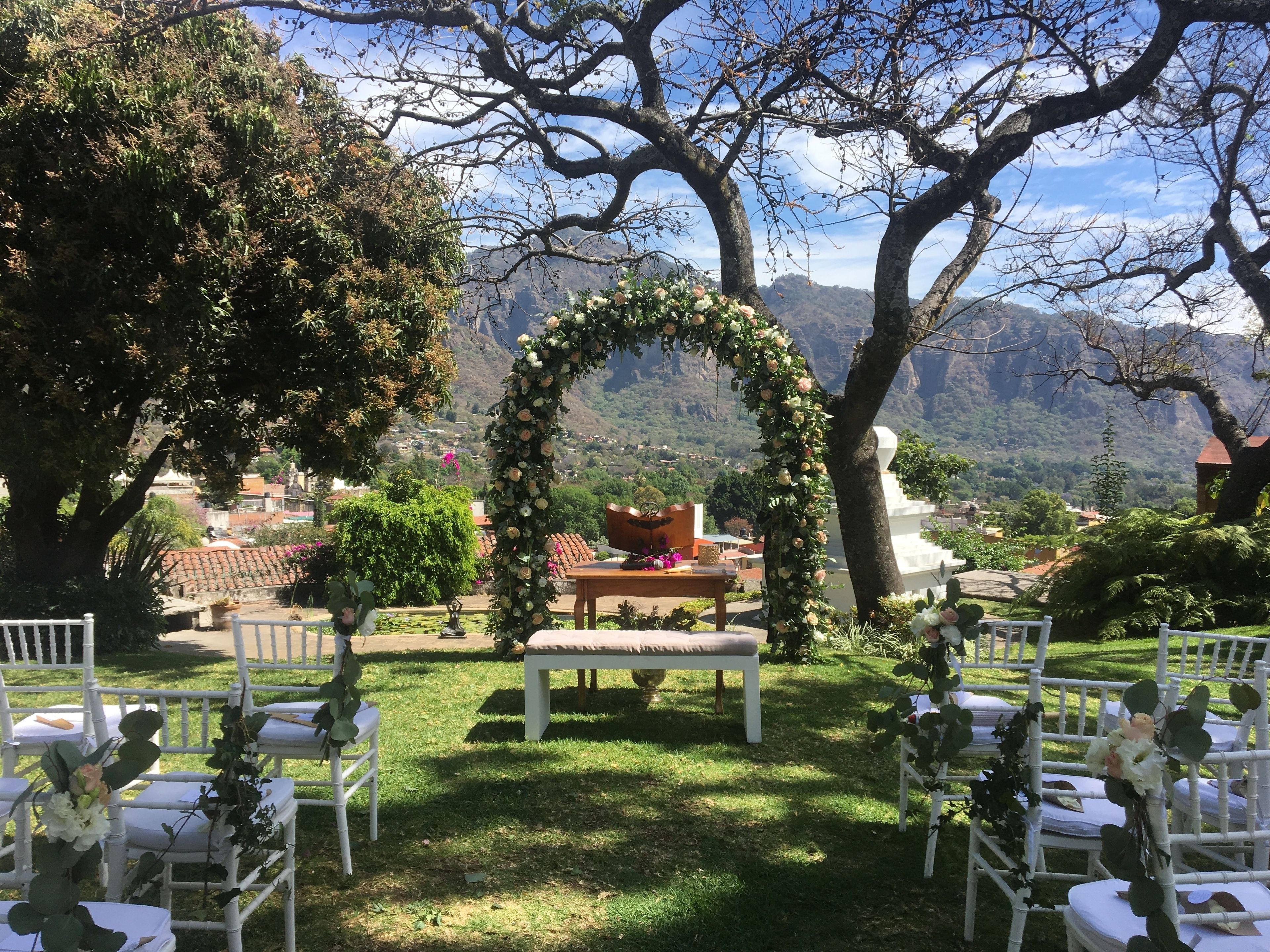 An outdoor wedding setup with a floral arch and seating.