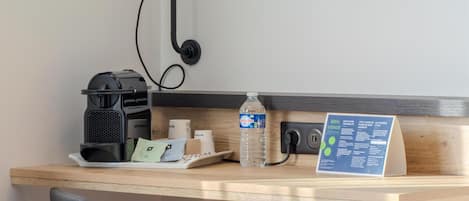 Un bureau avec une machine à café, une lampe, une bouteille d’eau, un panneau indiquant le menu et une chaise.
