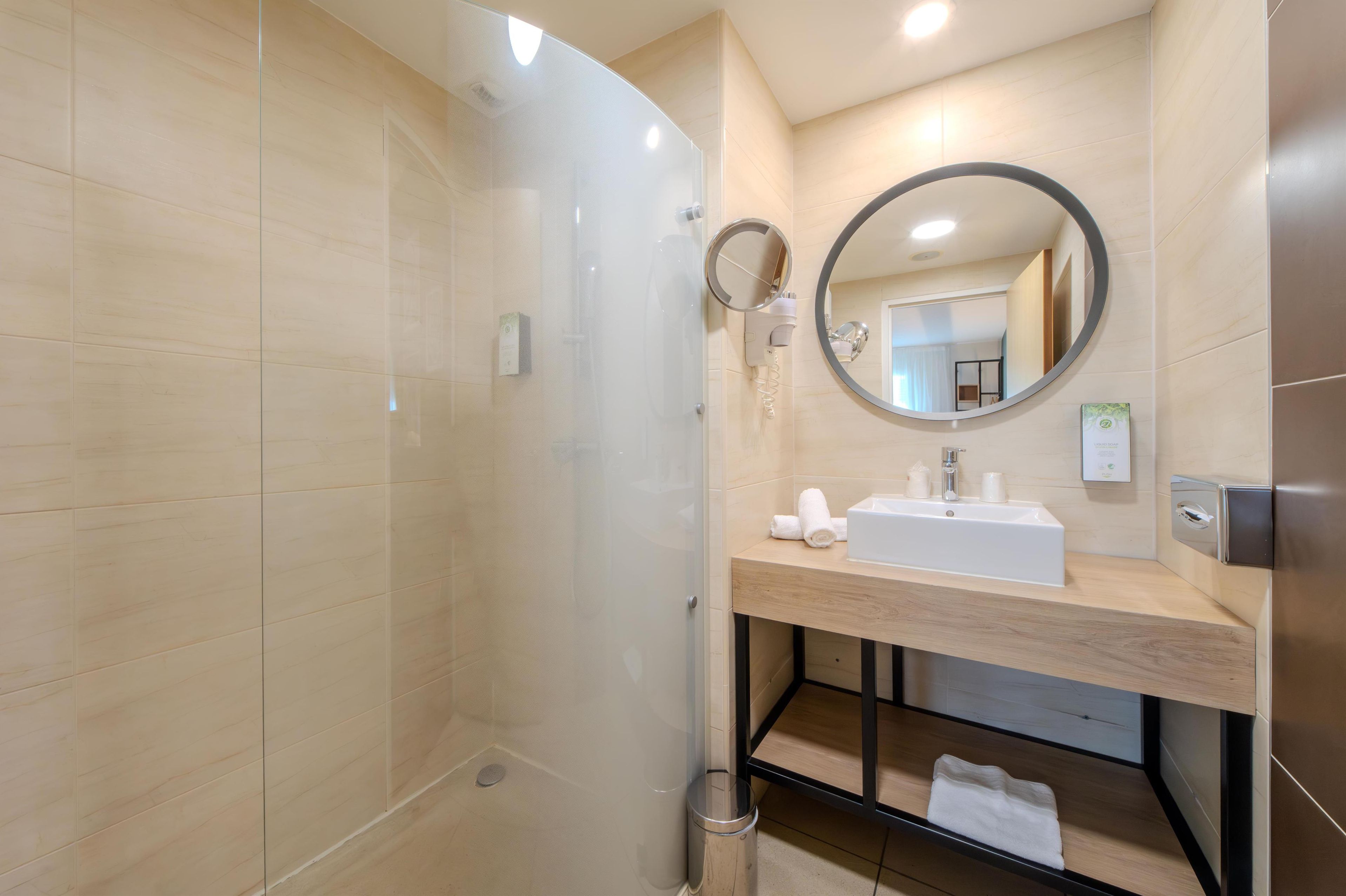 Une salle de bain moderne avec une douche à parois de verre, un lavabo avec un miroir et un porte-serviettes.