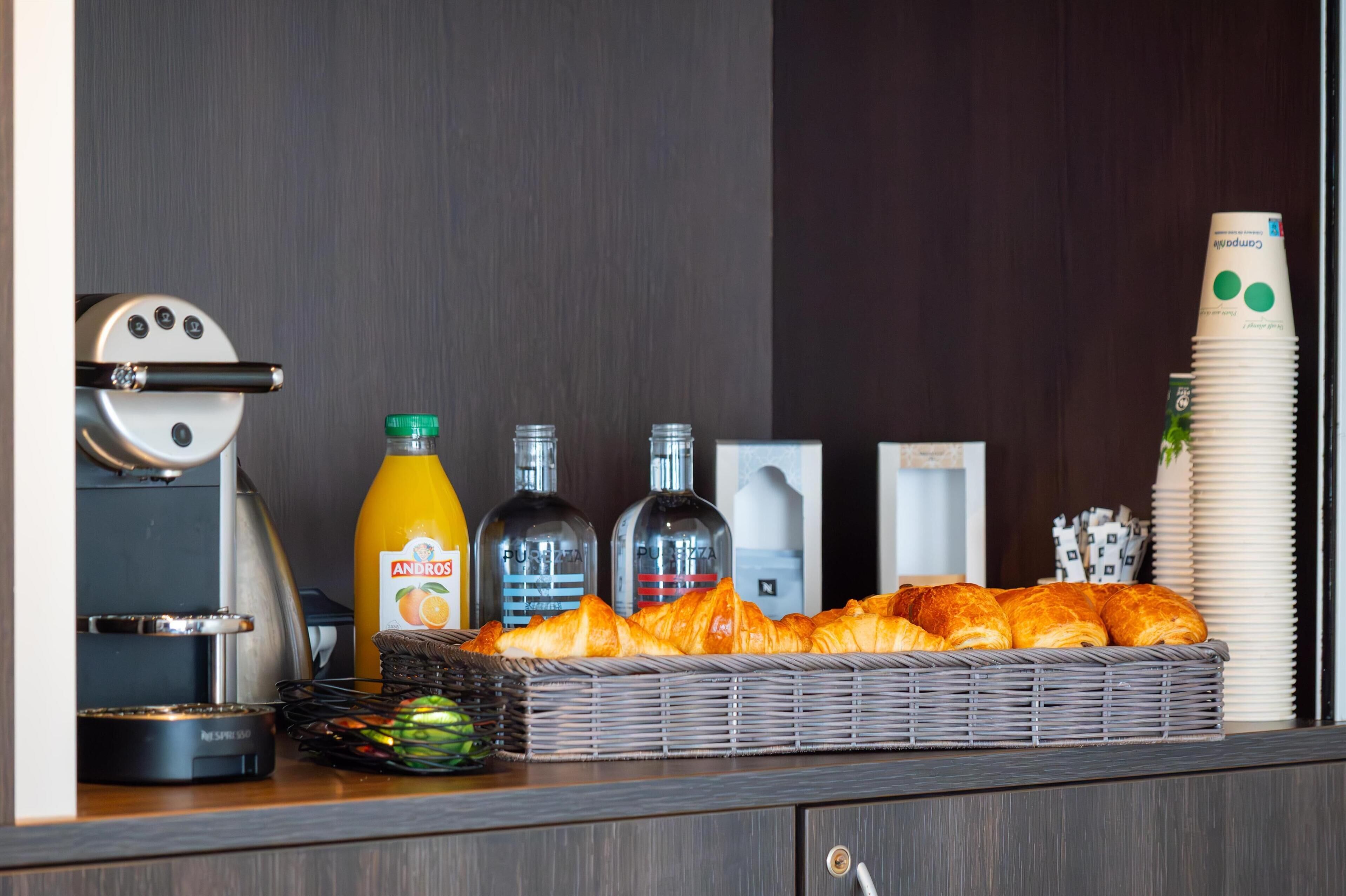 En morgenmadsbuffet med croissanter, juice og vand på flaske.