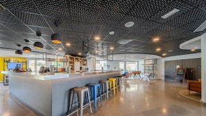 Un área de bar moderna con mostrador, taburetes e iluminación colgante.