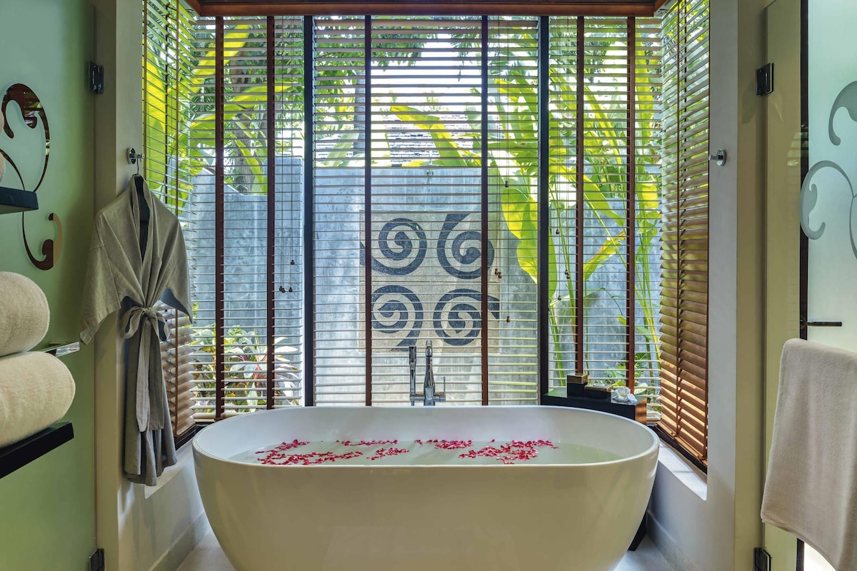 Un baño con una bañera independiente, un perchero y una ventana con persianas.