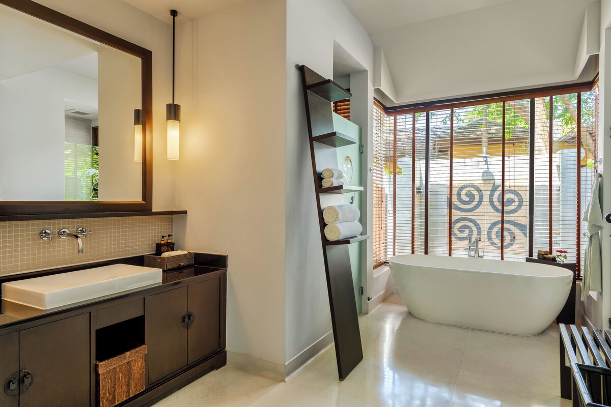 A modern bathroom with a large bathtub, a double sink vanity, and a large mirror.