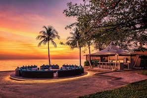 A beachside lounge with a circular seating area, a bar, and a gazebo.