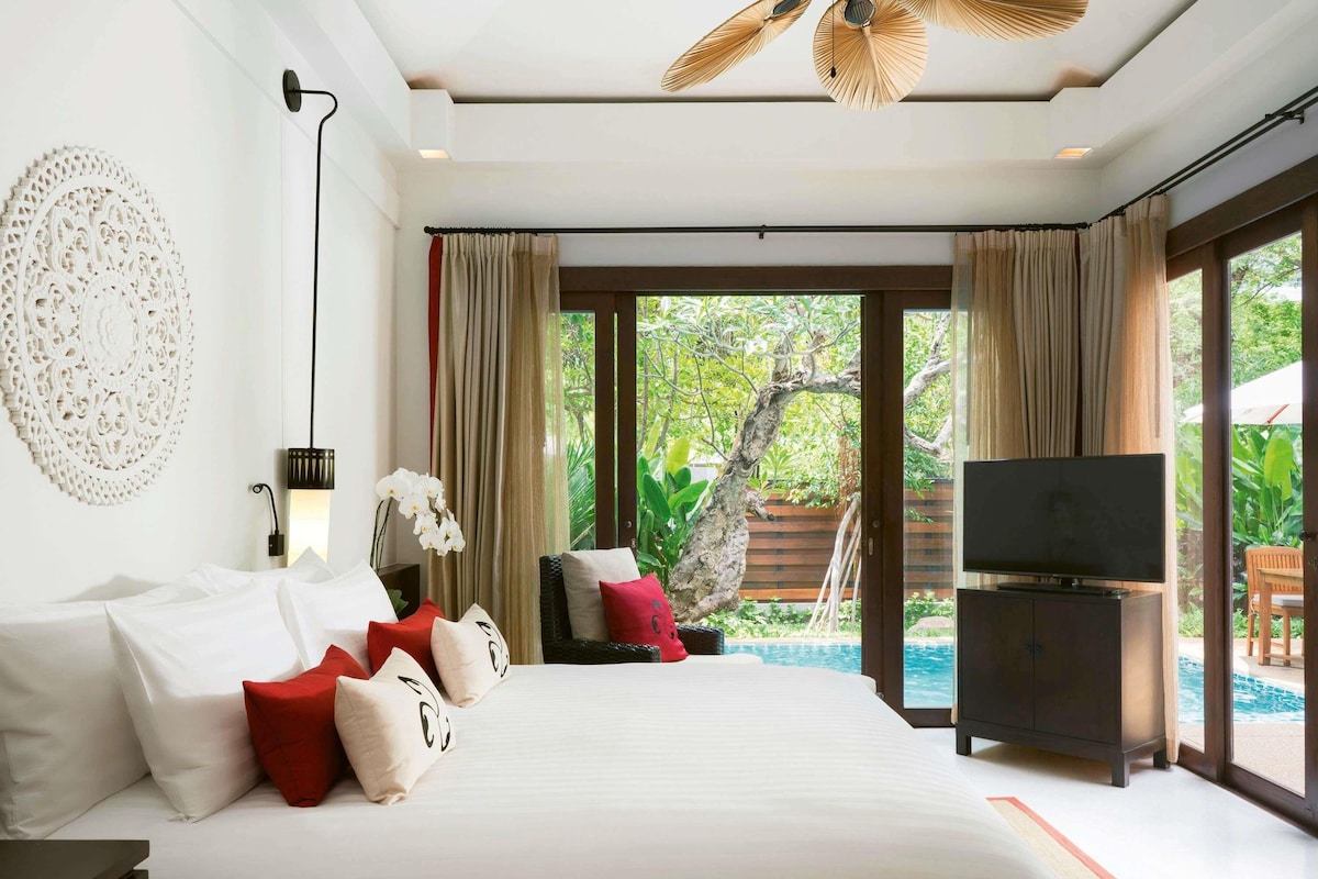 Habitación de hotel con una cama grande, televisión y vista a una piscina.