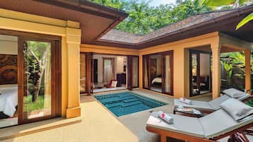 A hotel suite with a private pool, a sitting area with a table and chairs, and a bedroom with a large window.