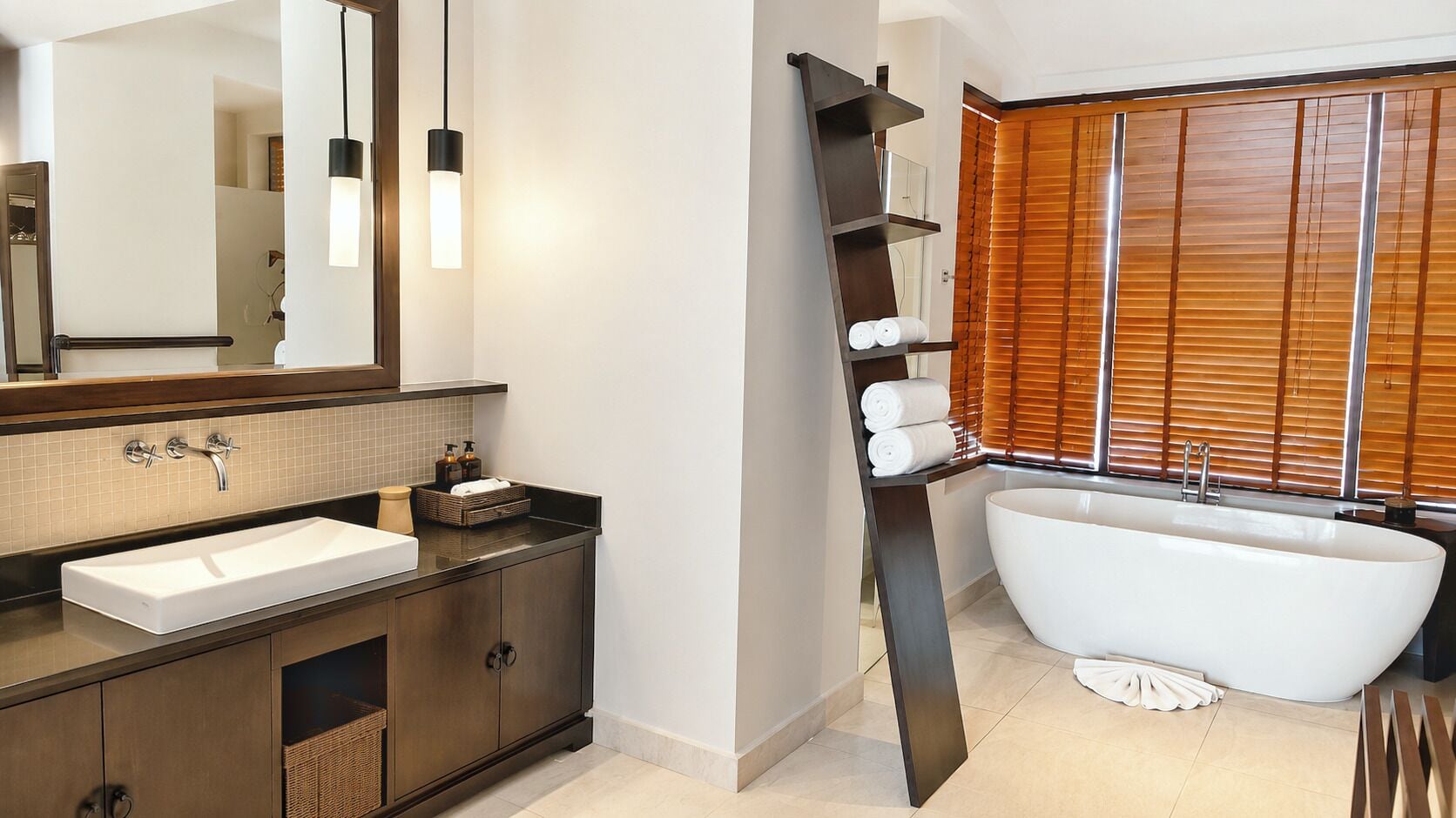 A modern bathroom with a freestanding bathtub, a large mirror, and a vanity with a sink and storage.