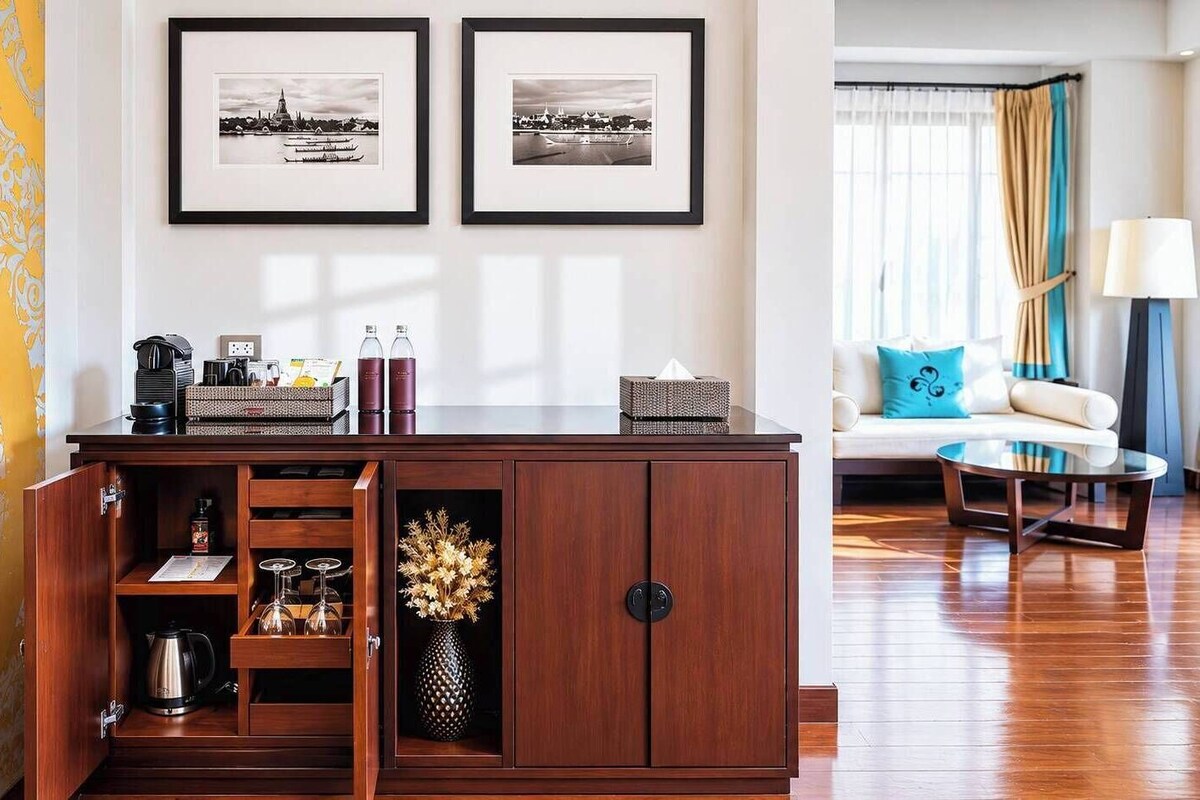 A wooden cabinet with a wine rack, a vase with dried flowers, and two framed black-and-white photographs on the wall.