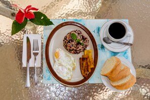 A breakfast plate with rice, eggs, plantains, and toast, accompanied by a cup of coffee and a flower. - Villas Hermosa Heights (Sardinal)