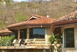 A building with a tiled roof, large windows, and a balcony with chairs and plants. - Villas Hermosa Heights (Sardinal)