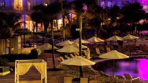 Un hôtel à plusieurs étages doté de balcons, d’un espace piscine avec des chaises longues et des parasols, ainsi que d’un bassin décoratif.