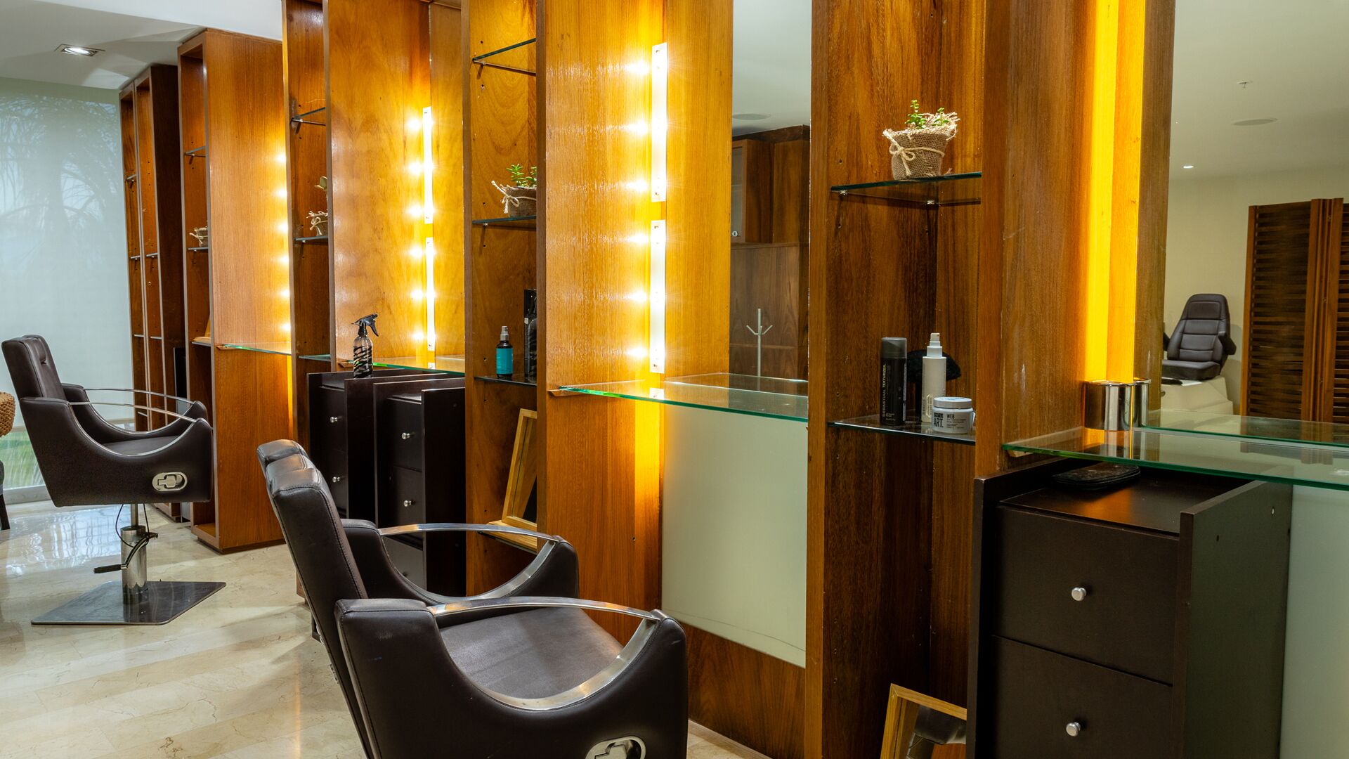 Un salón moderno con paneles de madera, vitrinas de cristal y sillas de peluquería negras.