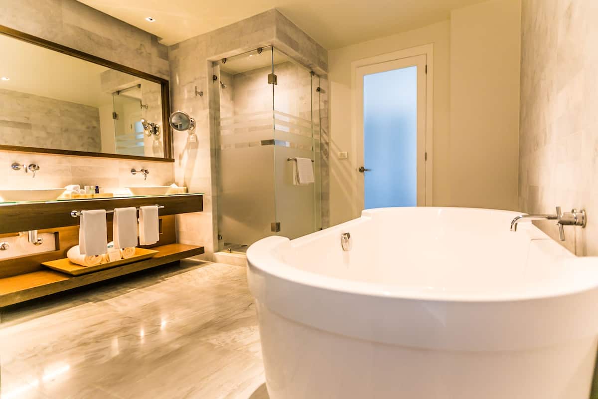 A modern bathroom with a large bathtub, a glass-enclosed shower, and a vanity with a mirror and towel rack.