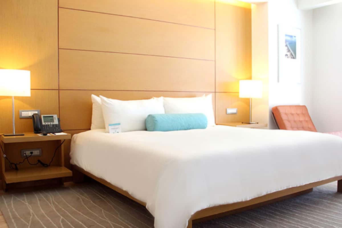 A hotel room with a large bed, two bedside tables with lamps, a telephone, and a chair.