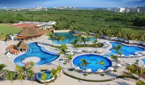 Un complexe hôtelier doté de plusieurs piscines, de palmiers et offrant une vue sur l’océan.