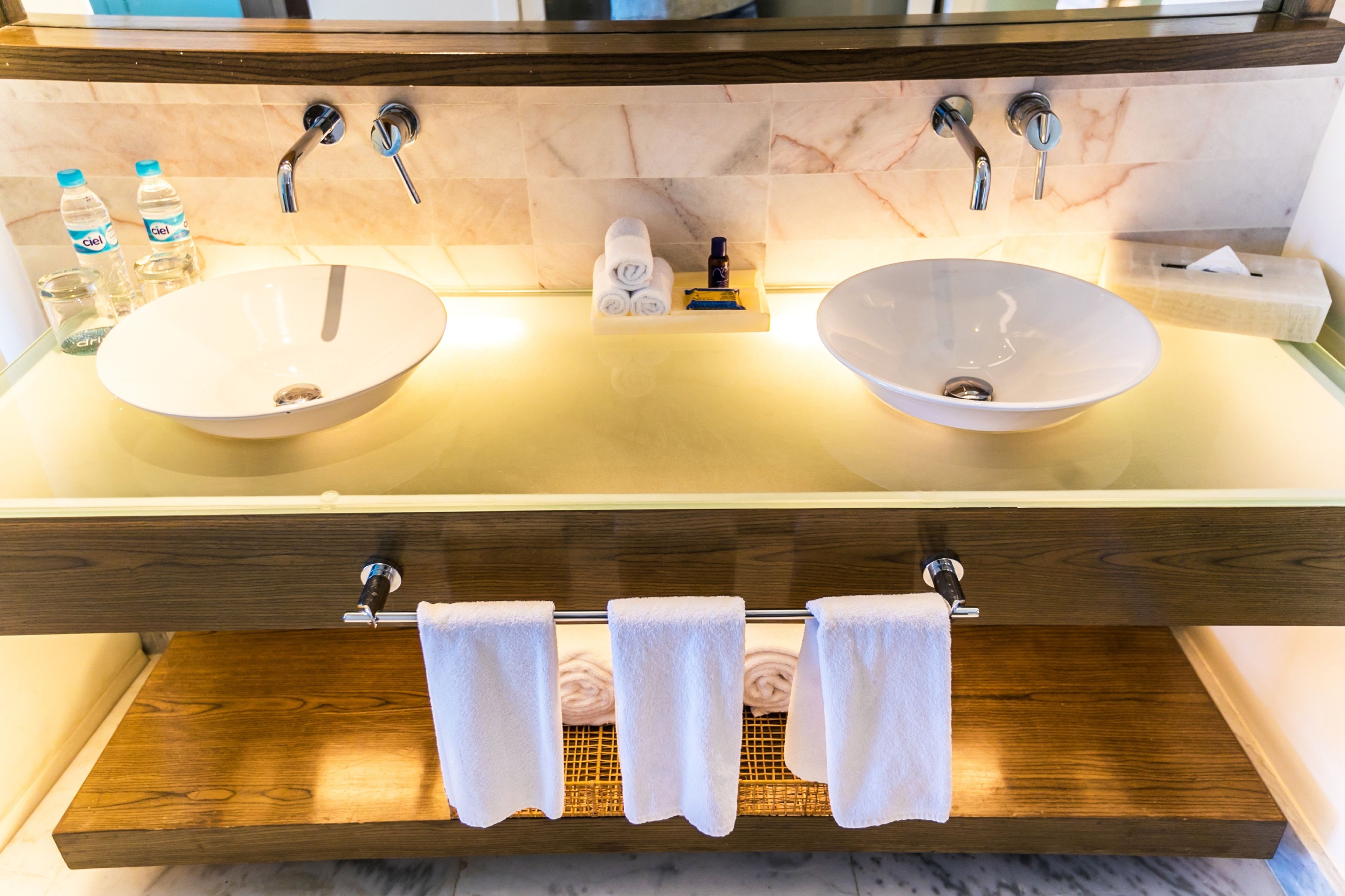 Un baño con dos lavamanos, un perchero para toallas y artículos de aseo.