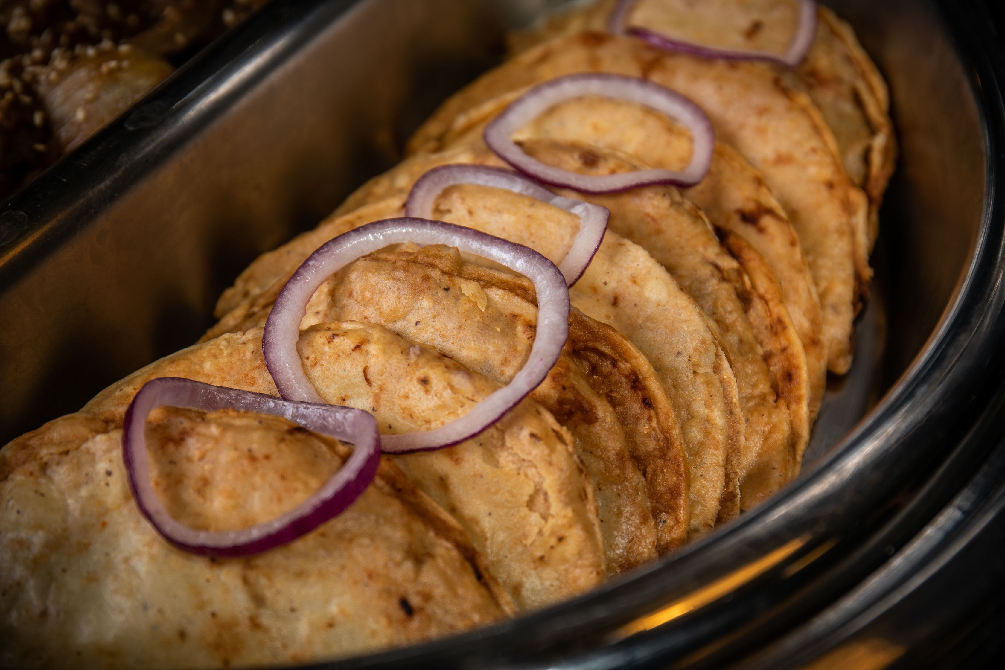 Una hogaza de pan con rodajas cubiertas de aros de cebolla roja.