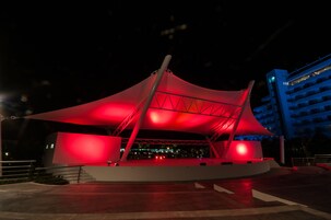 Un edificio moderno con una estructura roja iluminada y fachada blanca.