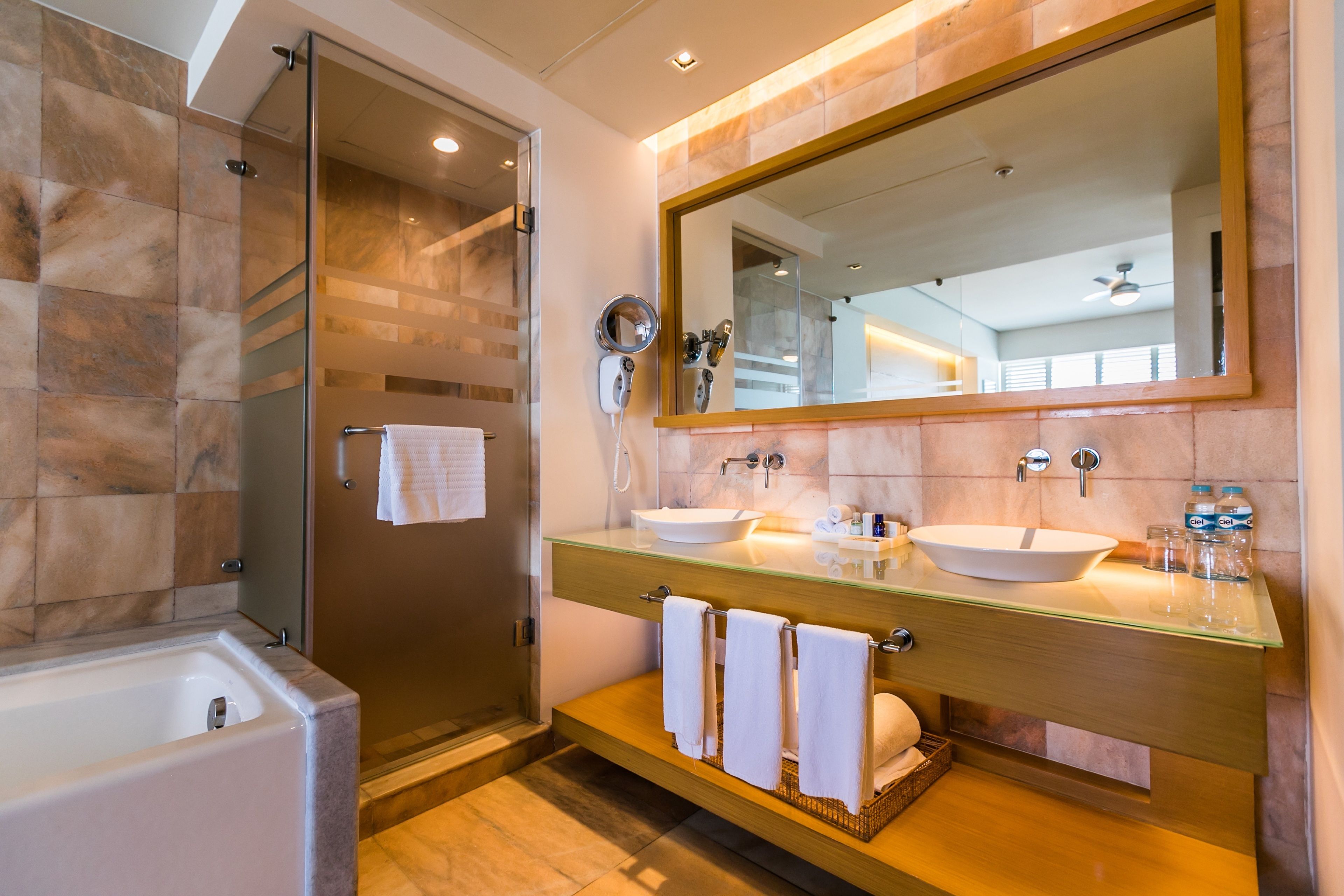 A modern bathroom with a glass-enclosed shower, two sinks, and a large mirror.