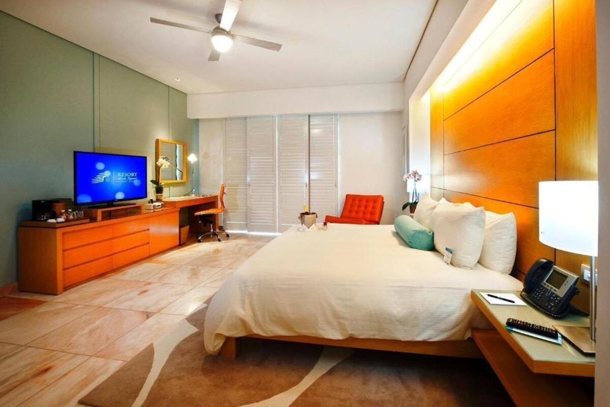 A modern hotel room with a large bed, a television, a desk, and a chair.