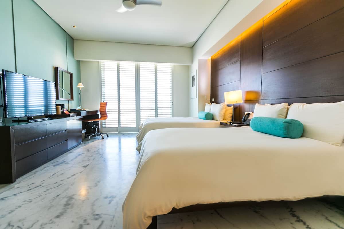 A modern hotel room with a large bed, a desk, and a television.