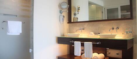 A modern bathroom with two sinks, a large mirror, and a shower area.