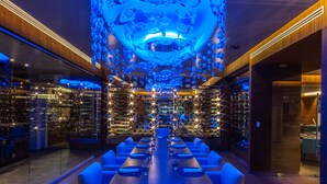 Un restaurant doté d’une longue table, d’un éclairage bleu et d’un décor de plafond original.