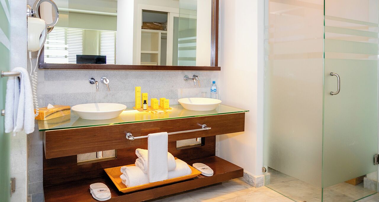 A bathroom with two sinks, a mirror, and a towel rack.