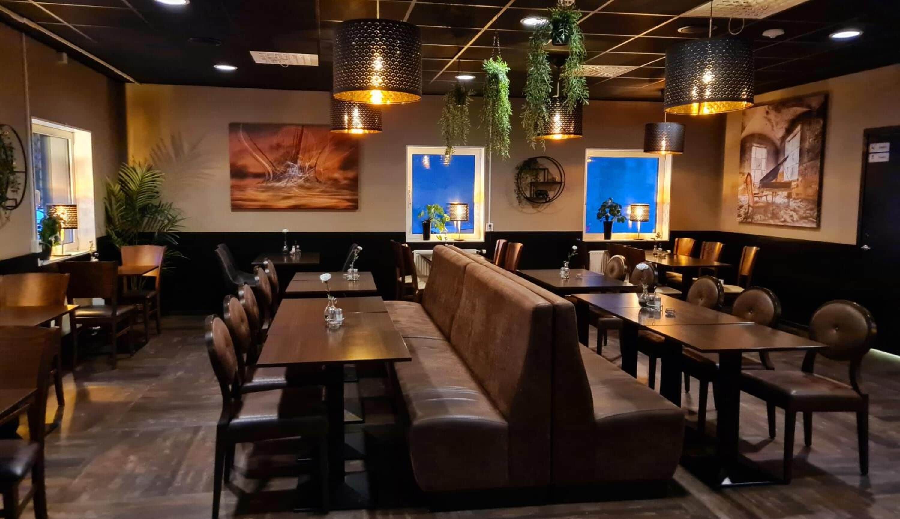 Ein Restaurant mit einer langen Theke, Sitzecken und hängenden Pflanzen.