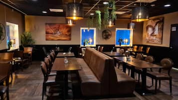 Ein Restaurant mit einer langen Theke, Sitzecken und hängenden Pflanzen.