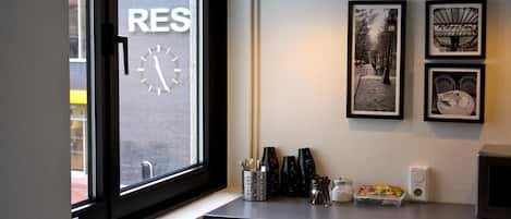 Una cocina con ventana, un reloj y cuadros en la pared.