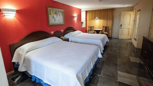 Una habitación de hotel con dos camas, un escritorio, una silla y una puerta.