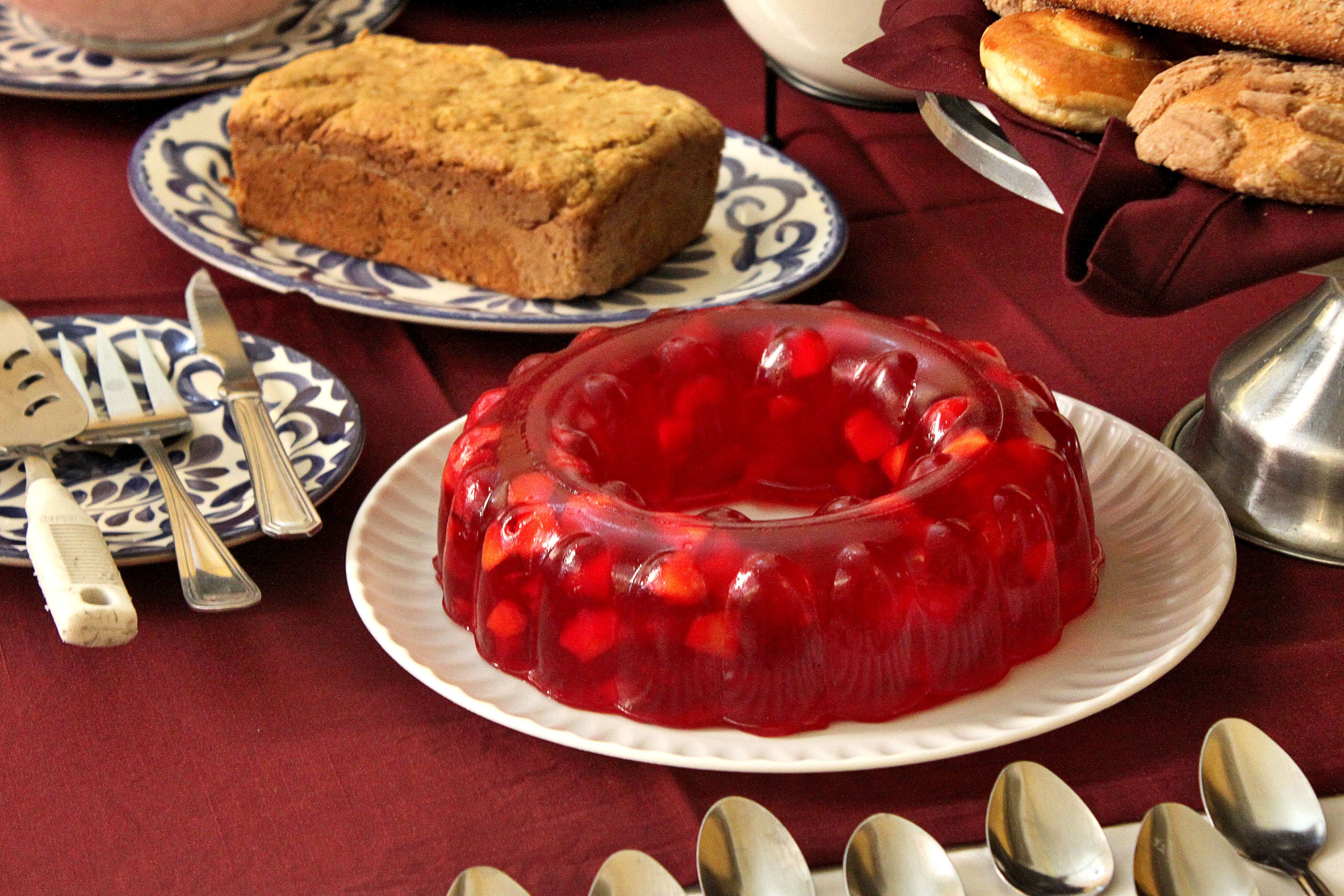 A dessert plate with a red jelly dessert and a slice of cake on a table with a red tablecloth.