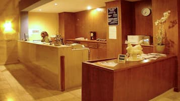 A reception area with a wooden reception desk, a clock, and a bulletin board.