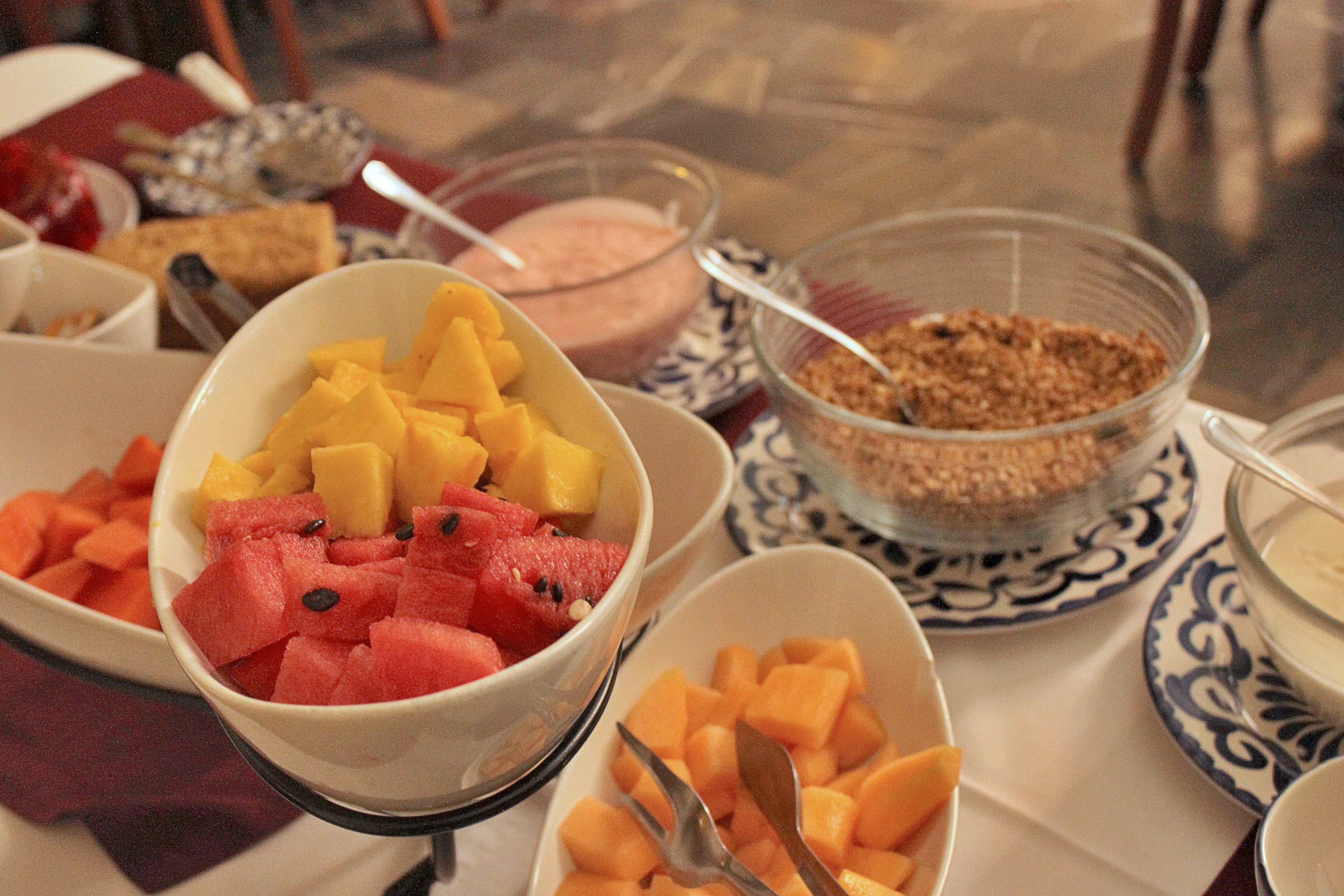 Una mesa con diferentes recipientes con frutas y un tazón de granola.