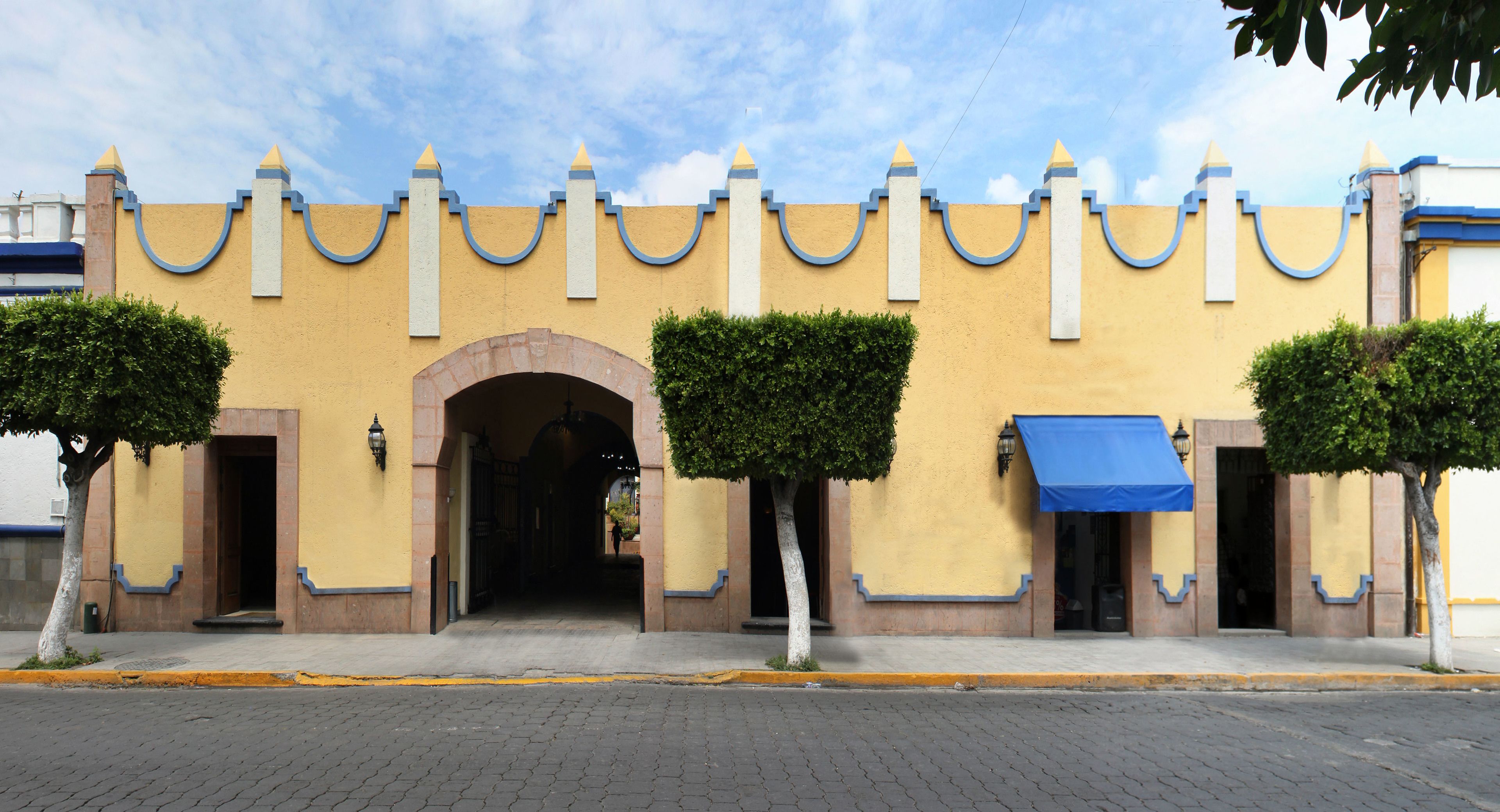 Ein Gebäude mit gelber Fassade, blauem Zierdekor und einem zentralen Bogen.