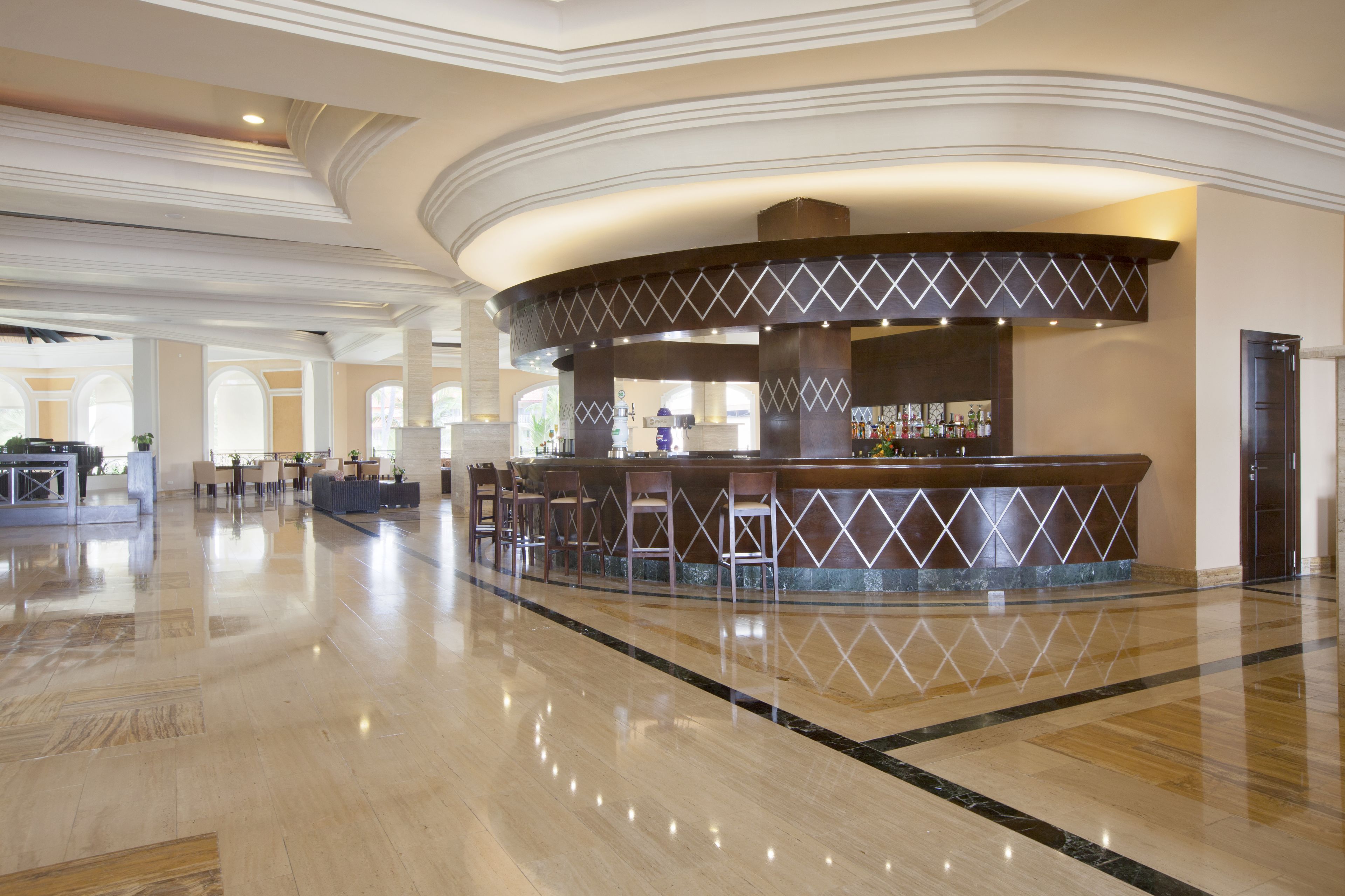 A spacious lobby with a central bar area, seating arrangements, and a polished floor.