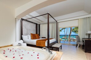 A four-poster bed with a view of the ocean, a large bathtub with rose petals, and a balcony with a view of palm trees and the sea. - Majestic Elegance Punta Cana - All Inclusive (Punta Cana)