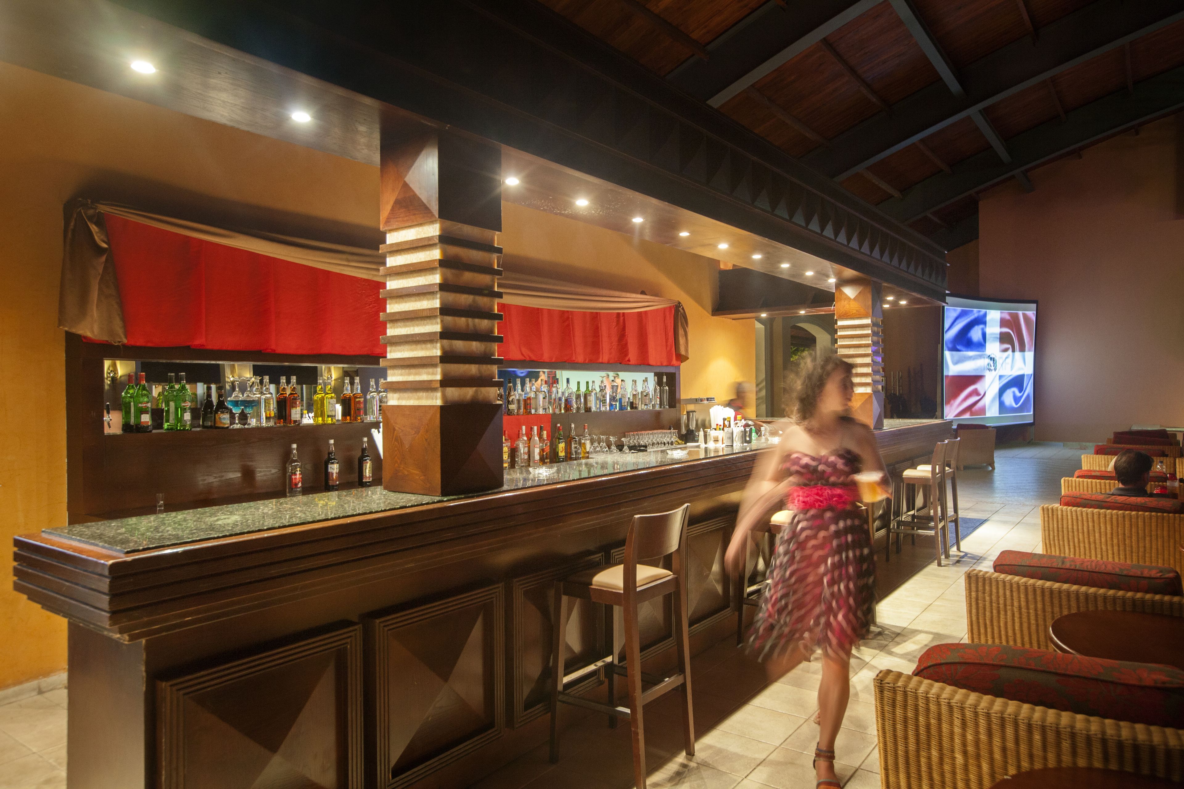 Zona de bar con mostrador, taburetes y una pantalla de televisión.